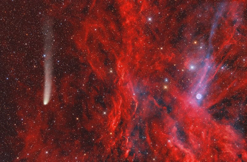 A bright comet with a glowing tail streaks through a star-filled sky, surrounded by vivid red and blue nebula clouds and distant stars, creating a vibrant cosmic scene.