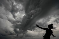 Storm clouds roll across DFW International Airport over the “Share the Dream” sculpture at...