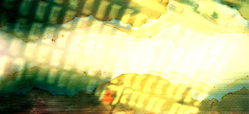 Abstract image with green, yellow, and white watercolor-like washes, textured with horizontal lines and areas of shadow and light. Some distorted, fence-like patterns are visible, creating a dynamic, layered effect.