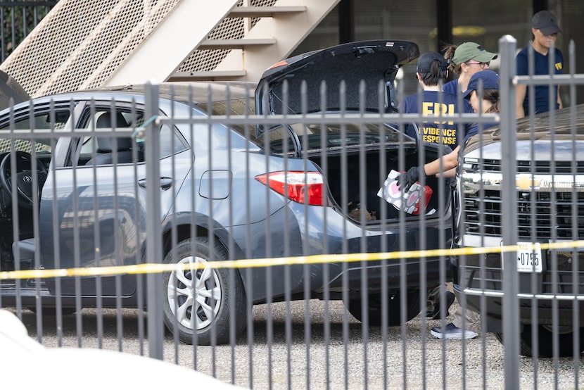 FBI officials investigate a vehicle outside of the an immigration attorney office behind the...
