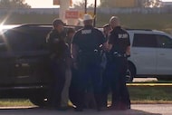 Law enforcement officials investigate a vehicle near the scene of a deadly shooting shooting...