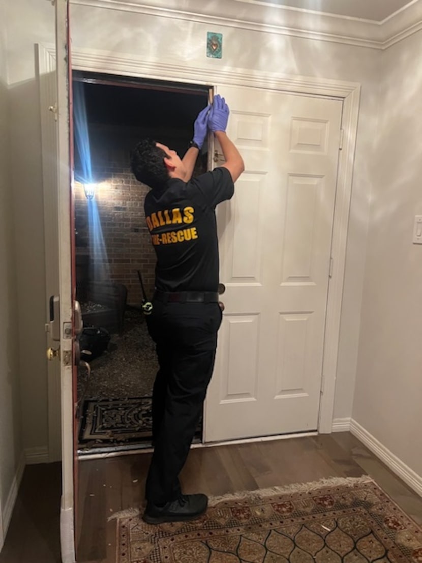 A Dallas Fire Rescue officer tries to repair Deborah Kane's door after officers knock it...
