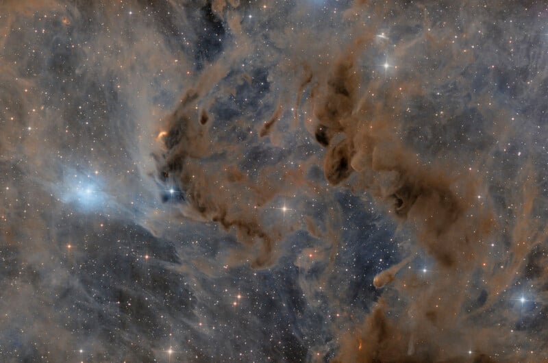 A vibrant view of a star-filled nebula, with bright stars scattered amid swirling clouds of blue, brown, and orange cosmic dust and gas against a dark space background.
