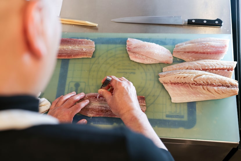Chef Tatsuya Sekiguchi removes bones from cuts of fish as he prepares for service.