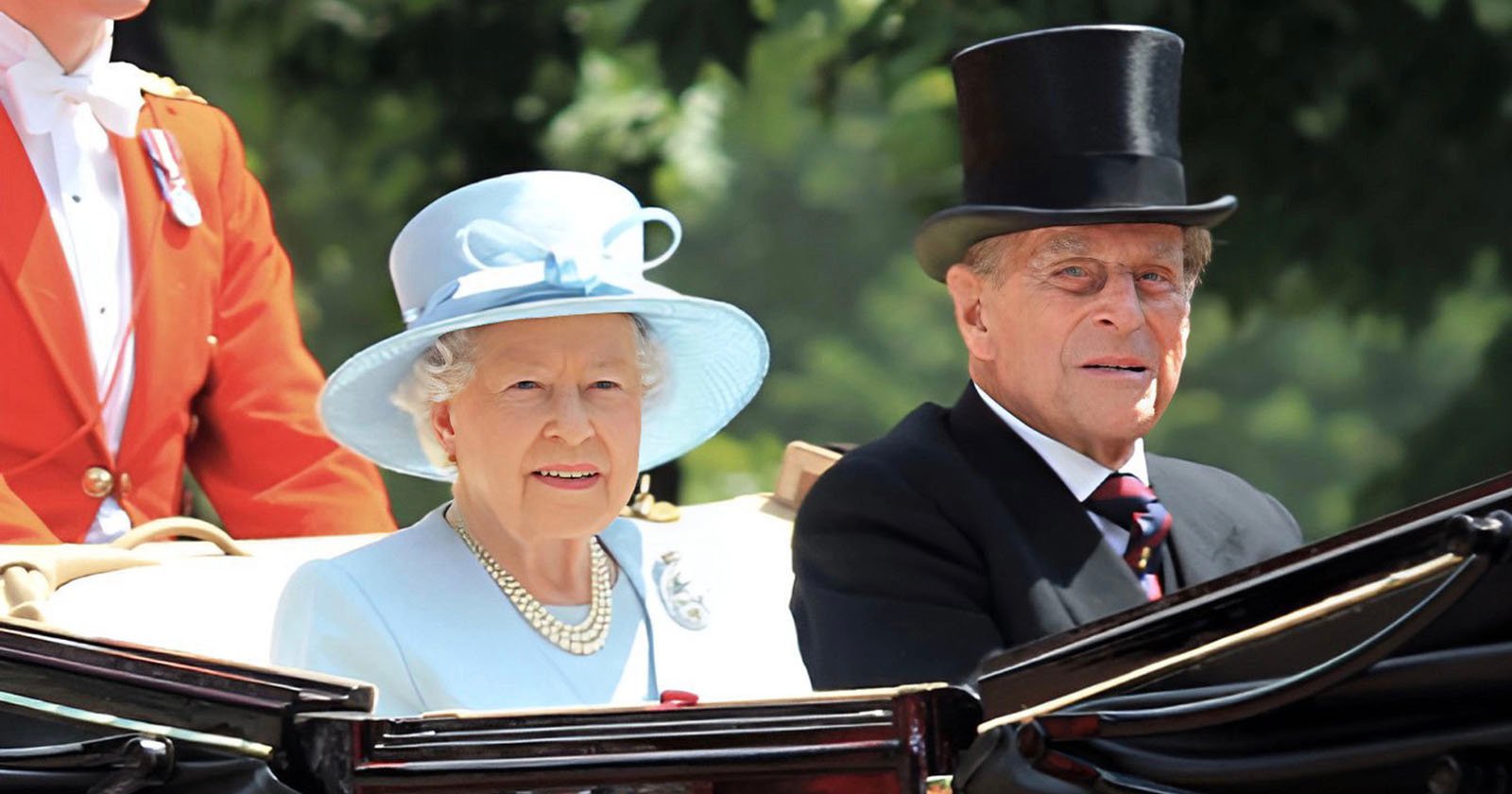 An elderly woman in a light blue outfit and hat sits beside an elderly man in a black suit and top hat in an open carriage, with another person in a red coat partially visible behind them. Trees are in the blurred background.