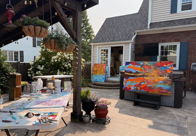 JoAnne Sharman's outdoor painting table and some of her recent works in front of her studio.