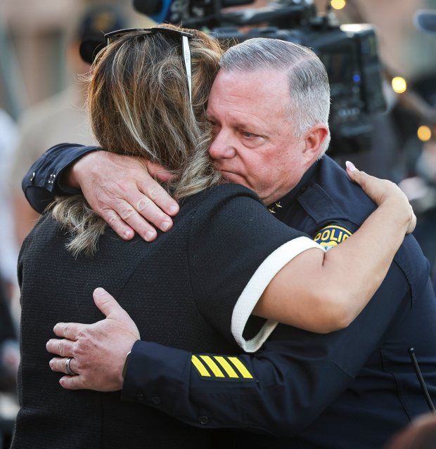 Nadia Zamora, owner of Pink Rose cafe, hugs La Mesa police Chief Ray Sweeney during a community candlelight vigil and fundraiser Friday in honor of La Mesa police Officer Lauren Craven, who was killed earlier this week. (Meg McLaughlin / The San Diego Union-Tribune)