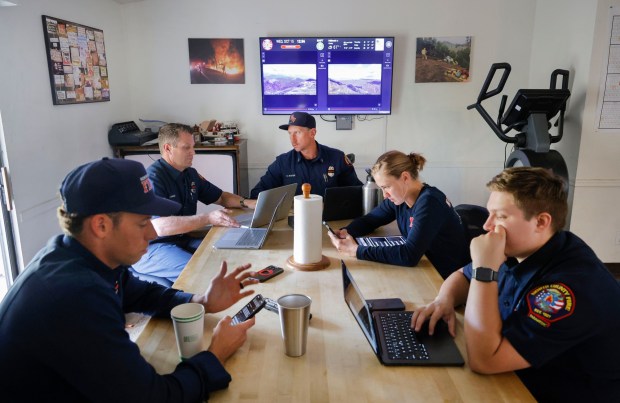 North County Fire Protection District Capt. Collin Baker, middle, meets with his team in the dining room of Station 4. (Charlie Neuman / For The San Diego Union-Tribune)