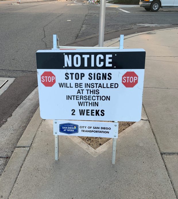 A city of San Diego sign notifying residents that stop signs will be installed at the intersection of Jackson Drive and Lake Badin Avenue was placed on a nearby sidewalk Thursday morning. (Shannon Smith)