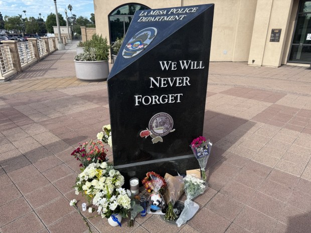 People left flowers at La Mesa Police Department on Tuesday, Oct. 21, at the base of a memorial for fallen officers. La Mesa officer Lauren Craven, 25, was struck and killed while on duty Monday night. (Hannah Elsmore/The San Diego Union-Tribune)