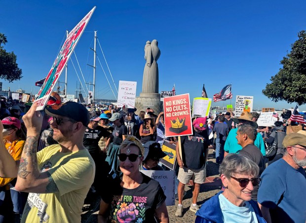 Protesters hold signs at the start of "No Kings" protests at Waterfront Park. (San Diego Union-Tribune/ Meg McLaughlin)