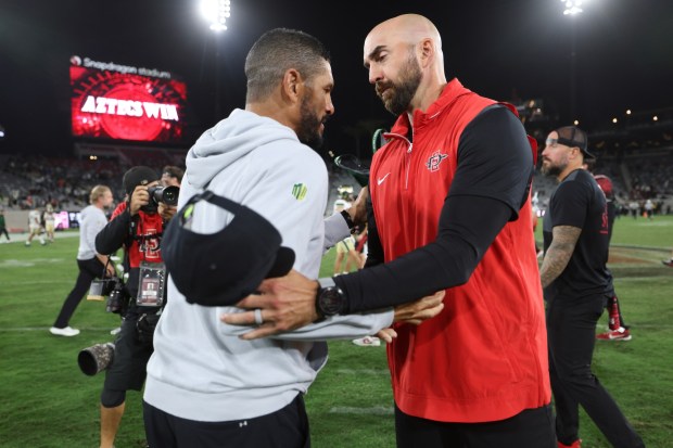 San Diego State coach Sean Lewis (right) and Colorado's State coach Jay Norvell speak briefly after SDSU beat the Rams. (Hayne Palmour IV / For The San Diego Union-Tribune)