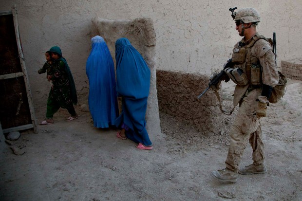 Cpl. Greg Dominguez, from Bonita, with 2/5, Fox Company conducting Operation Branding Iron in Lwar Bajigar, Afghanistan, escorts civilians away from the compound where his squad was to set and use as defensive position on July 6, 2012. (Nelvin C. Cepeda / The San Diego Union-Tribune)
