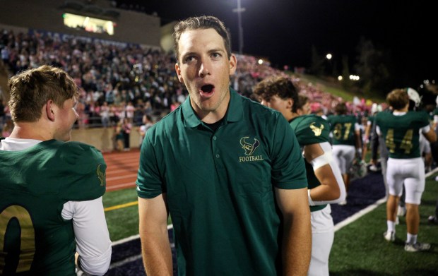 Former La Costa Canyon player Bruce Schram, a 2015 graduate and honorary team captain, lets out a yell from the sidelines as he and La Costa Canyon players get pumped up just before the starting kickoff against San Marcos at La Costa Canyon High School in Carlsbad on Friday, Oct. 10, 2025. (Hayne Palmour IV / For The San Diego Union-Tribune)