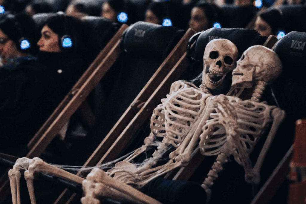 Image shows a pair of skeleton sculptures placed in seats at Rooftop Cinema Club.