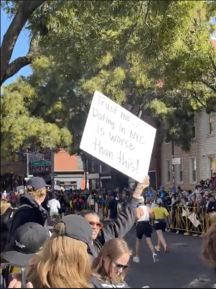 The sign reads:  “Trust me… dating in NYC is worse than this!”
