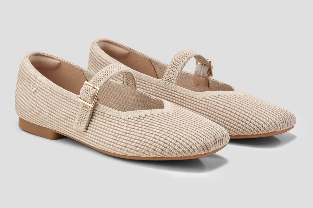 A pair of knitted beige Mary Jane style flats with buckle straps and brown soles.
