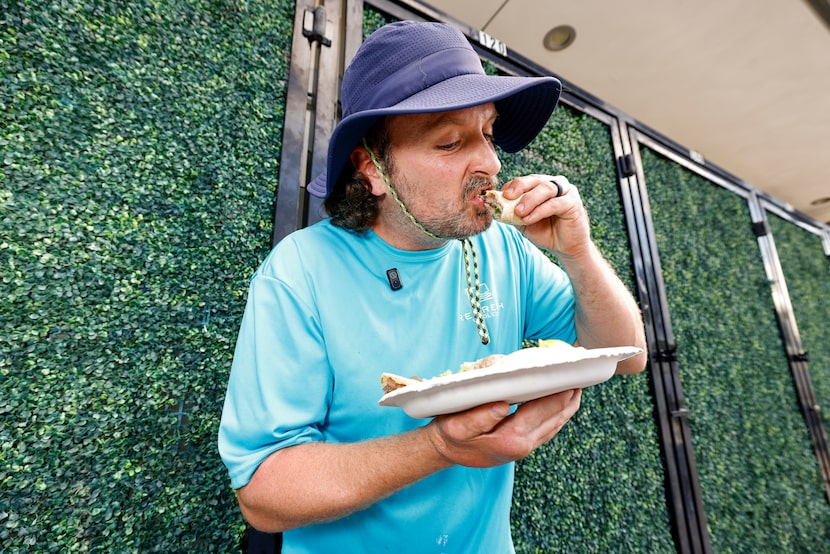 Drew Stephenson takes a bite of a taco at an El Califa de León taquería pop-up, Thursday,...
