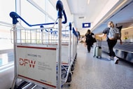 Travelers make their way down a baggage claim concourse at DFW International Airport,...