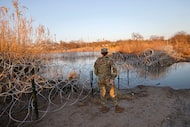 Texas National Guard Spc. Victoria Morgan stands by razor wire along the Rio Grande at...