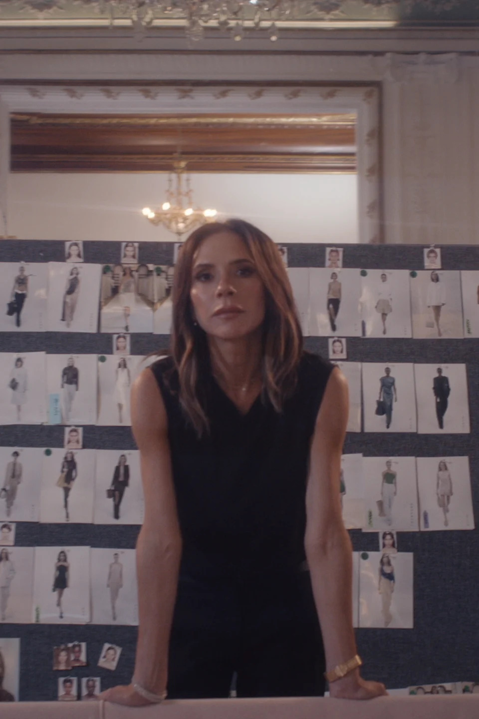 Victoria stands before a board of pinned-up fashion sketches in a scene from her Netflix documentary.