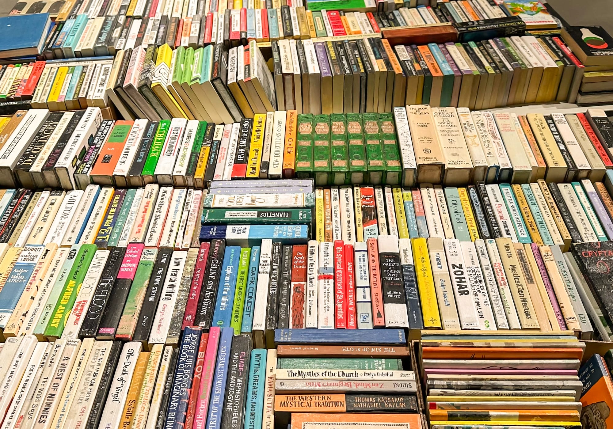 a collection of wooden and painted book sculptures by Conrad Bakker in boxes on a table