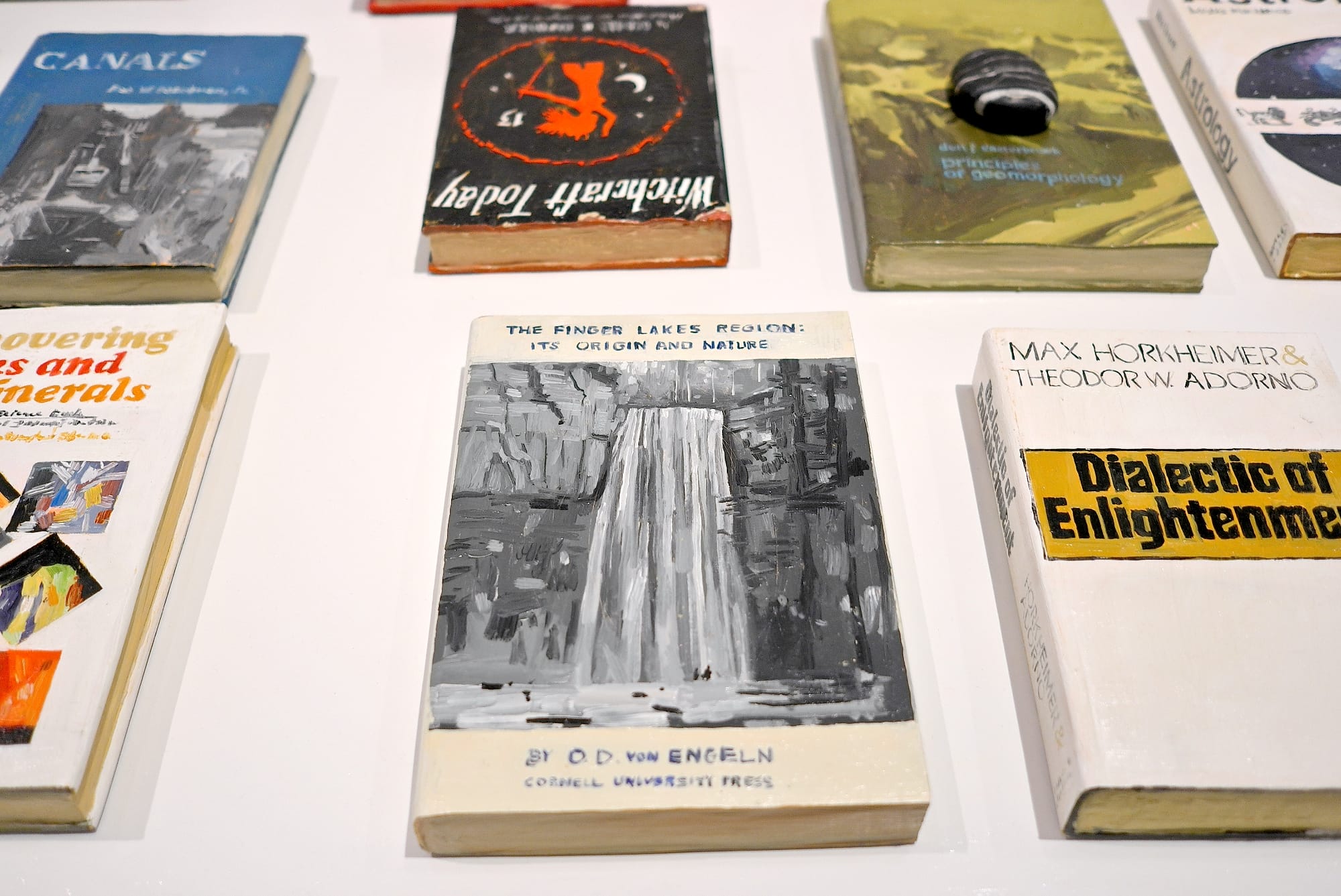 a collection of wooden and painted book sculptures by Conrad Bakker face up on a table