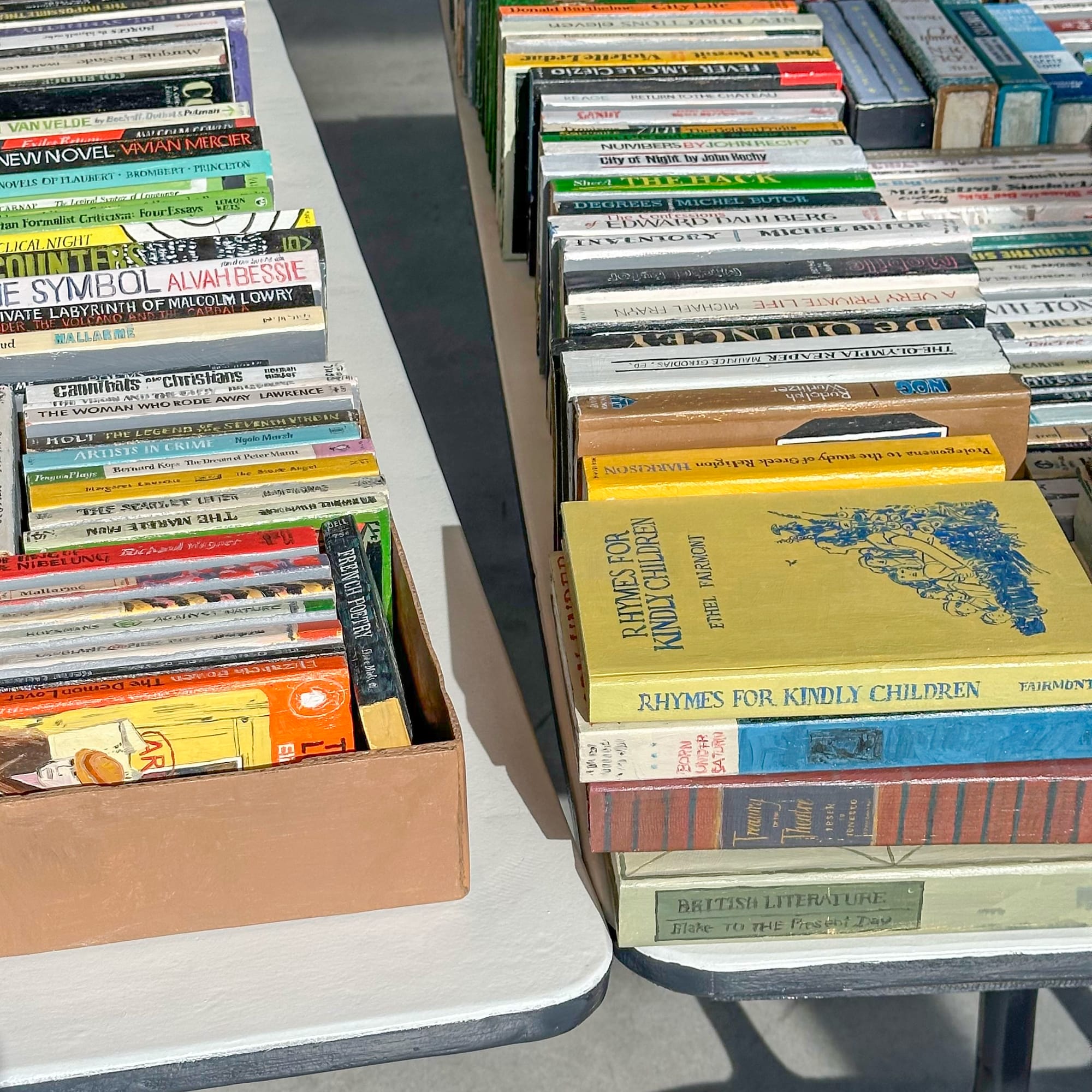 a collection of wooden and painted book sculptures by Conrad Bakker in boxes on a table