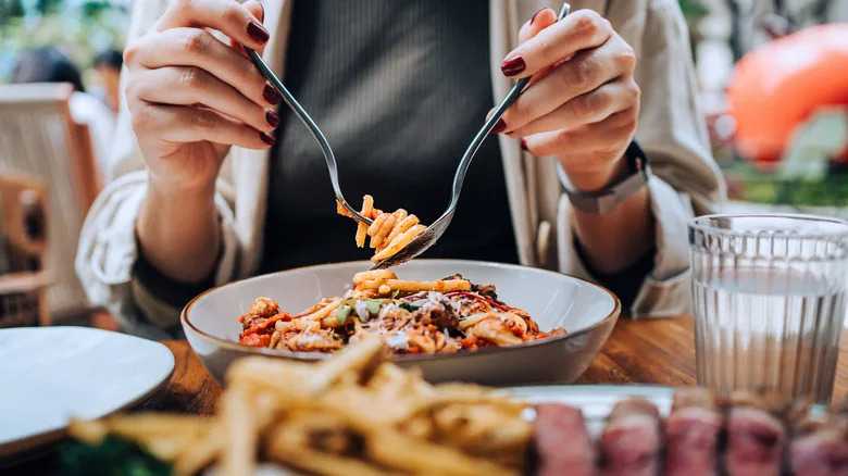 Woman eating spaghetti at table