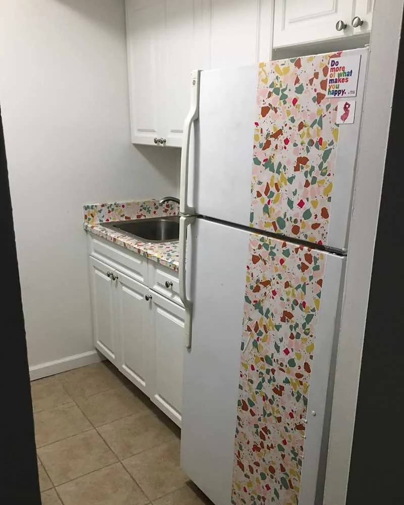 Small kitchen with white cabinets, a stainless steel sink, and a colorful terrazzo-patterned countertop and refrigerator.