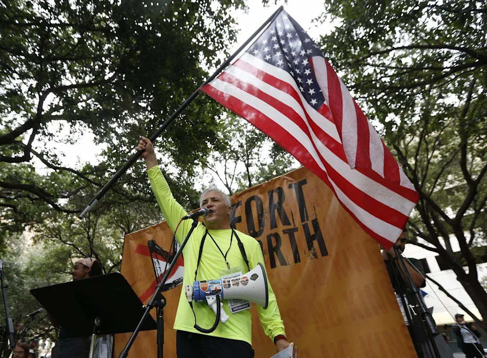 Benny Delavega waves an American flag as he speaks at the No Kings protest in Burk Burnett Park in downtown Fort Worth on Saturday, Oct. 18, 2025.
