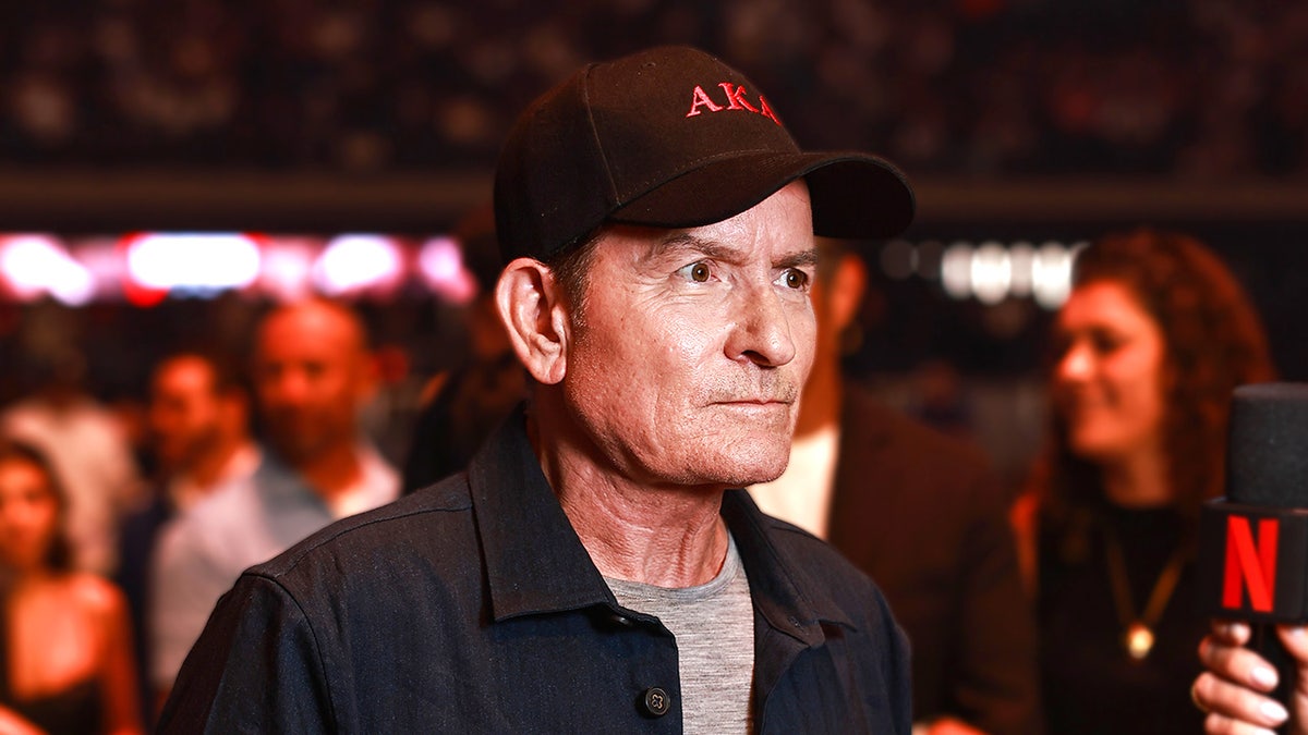 Charlie Sheen speaks into a microphone during an interview at the Canelo vs. Crawford boxing event in Las Vegas.