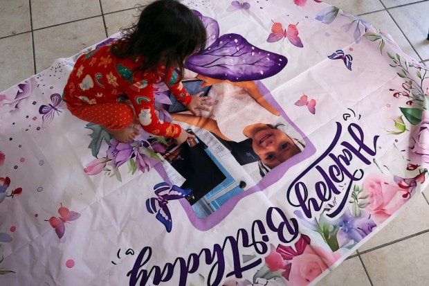 At home in Chicago, Nicolles plays with a birthday poster, Sept. 23, 2025, in advance of her fourth birthday. Days earlier, her father Darwin Leal was taken into custody by federal immigration officials. (Terrence Antonio James/Chicago Tribune)