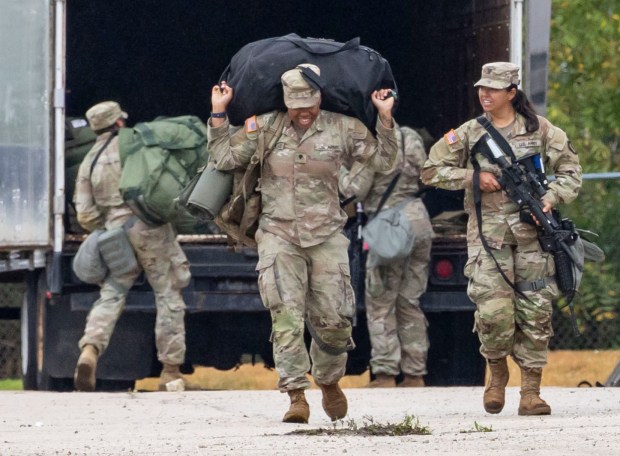 Members of the Texas National Guard carry luggage after arriving...