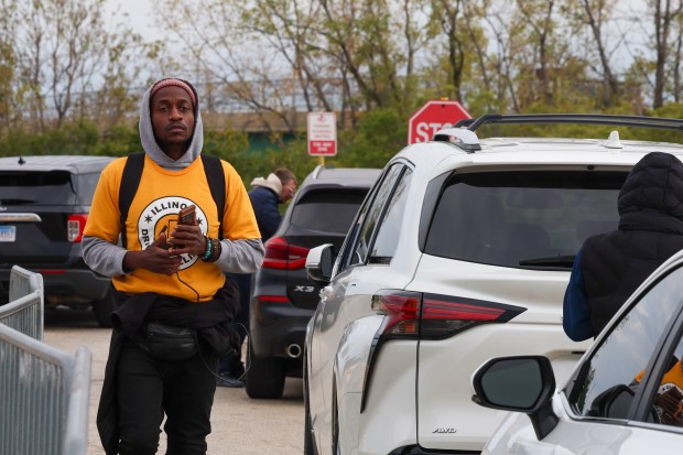 Herman Rome, a union organizer with the SEIU, walks near some of the half a dozen abandoned vehicles whose drivers were detained by federal agents in the Alpha Lot just outside of Chicago O'Hare International Airport on Oct. 25, 2025, in Chicago. The lot is frequented by rideshare drivers. Rome estimates 10-15 drivers were detained when federal agents swept the lot shortly after 1 pm. (Stacey Wescott/Chicago Tribune)