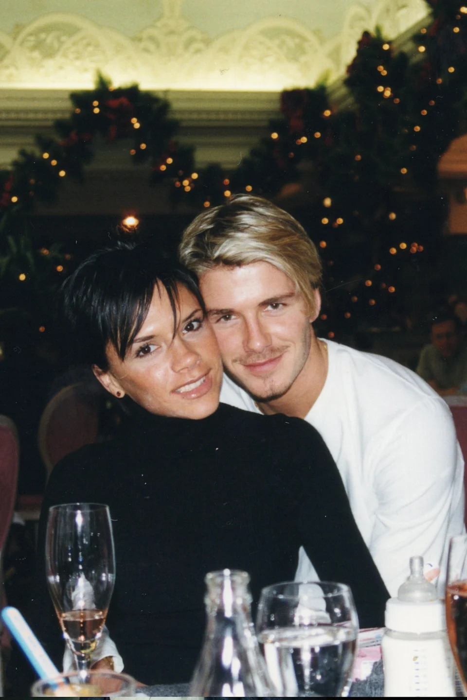 Victoria and David Beckham sit close together at a table early on in their relationship. 