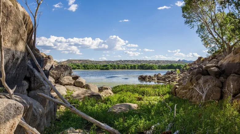 Scenic lakeside view at Willow Lake Granite Dells in Prescott Arizona with green moss, trees, blue sky and sunlight through rock cove
