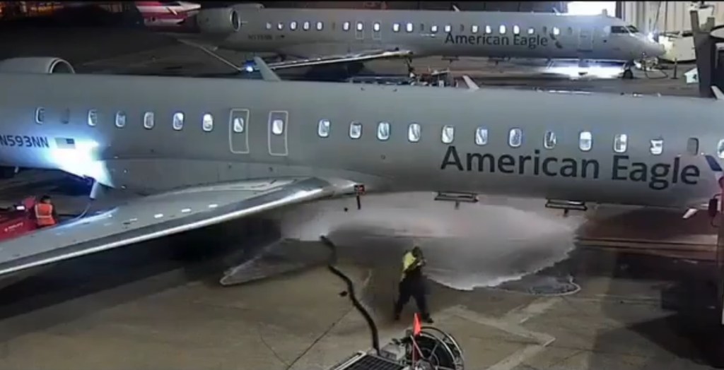 A ground worker loses control of a fuel hose, spraying liquid onto an American Eagle airplane.