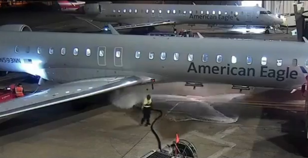 A Dallas Fort Worth Airport ground worker loses control of a fuel hose, spilling jet fuel on the tarmac near an American Eagle plane.