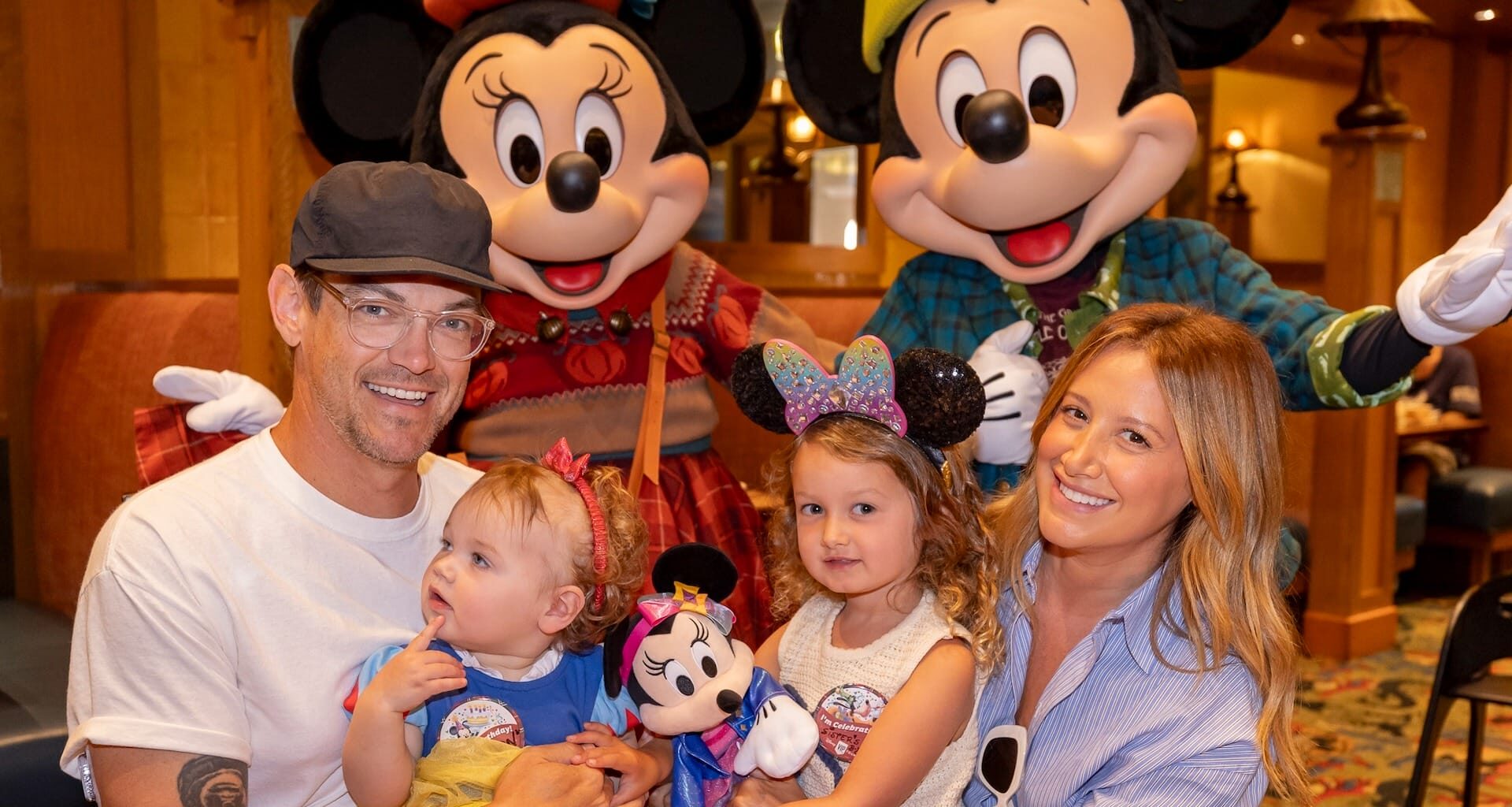 A happy family with two children poses with Mickey and Minnie Mouse at a Disney park restaurant, not far from Cinderella Castle.