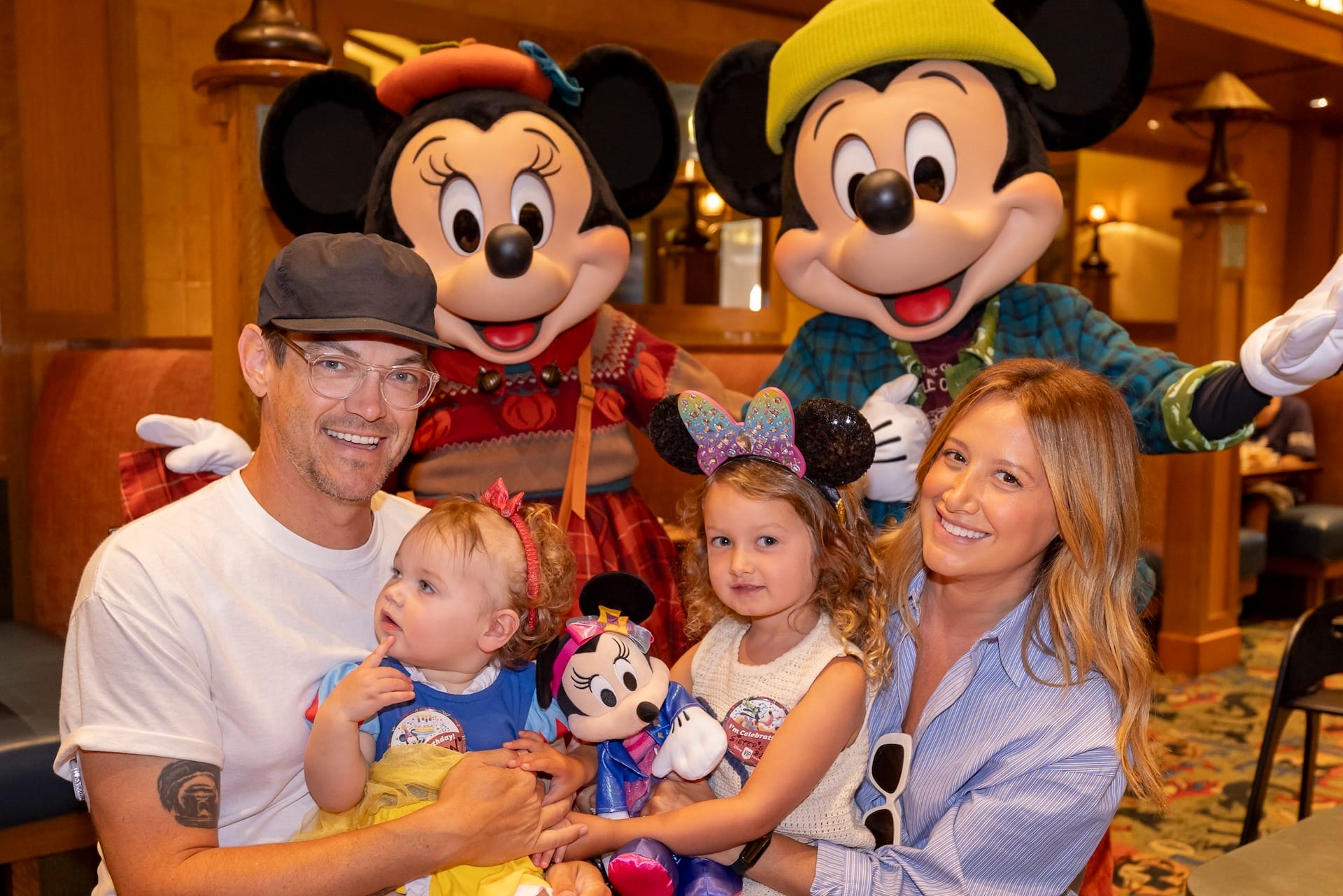A happy family with two children poses with Mickey and Minnie Mouse at a Disney park restaurant, not far from Cinderella Castle.