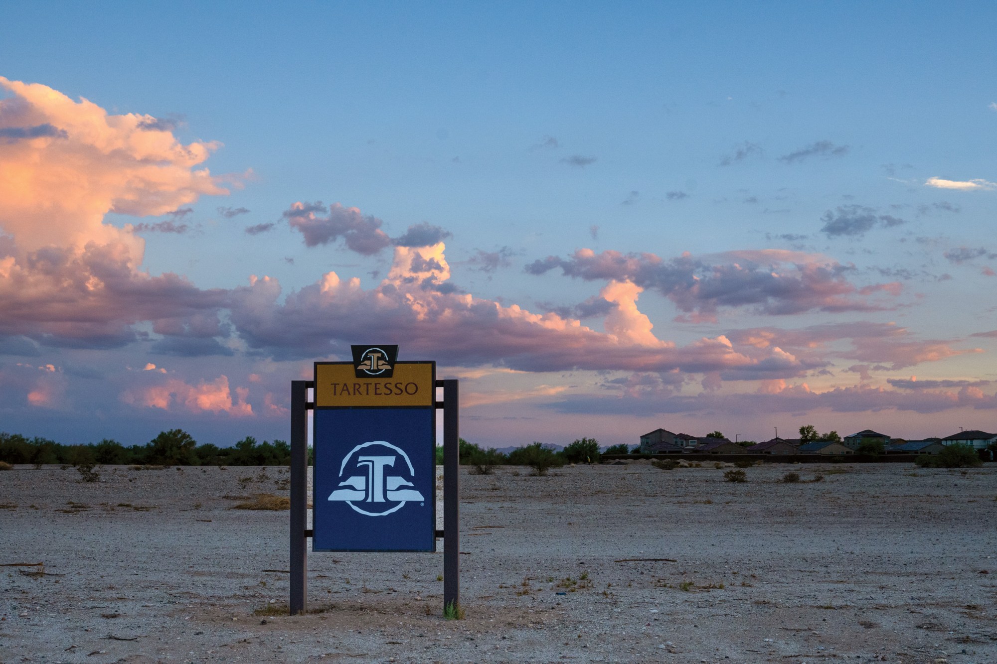 Clouds catch the last light of the day behind a sign for the Tartesso development in Buckeye, Arizona.
