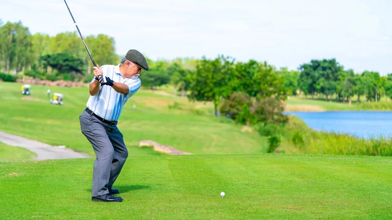 an elderly man plays golf