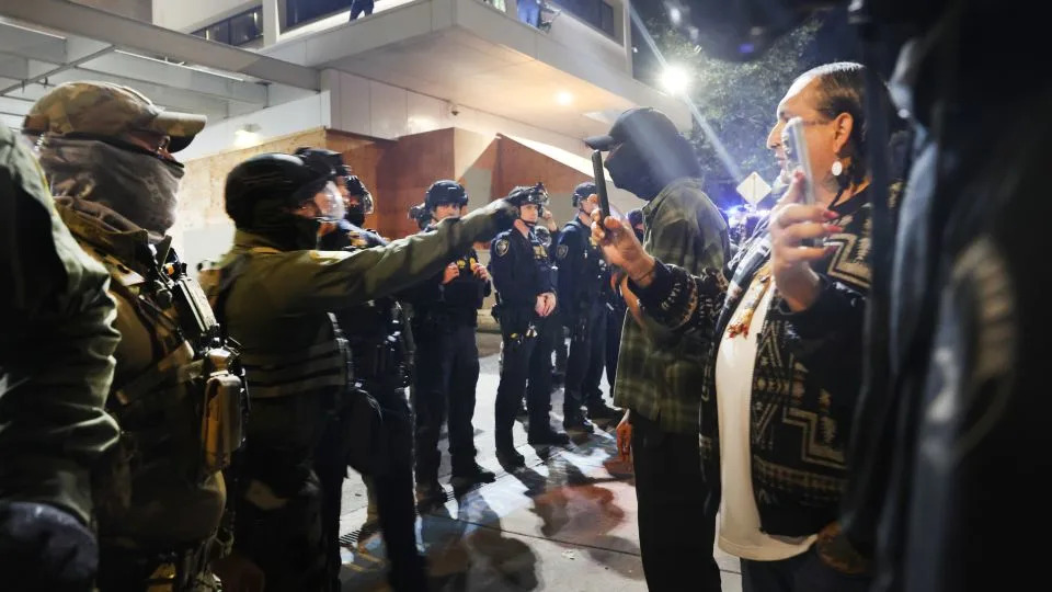 Federal agents, including members of the Department of Homeland Security, and the Border Patrol, hold back protesters outside a downtown U.S. Immigration and Customs Enforcement (ICE) facility yeseterday. - Spencer Platt/Getty Images