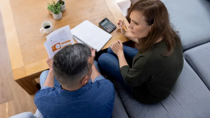A couple sitting at home having a serious discussion about their household budget and personal finances.