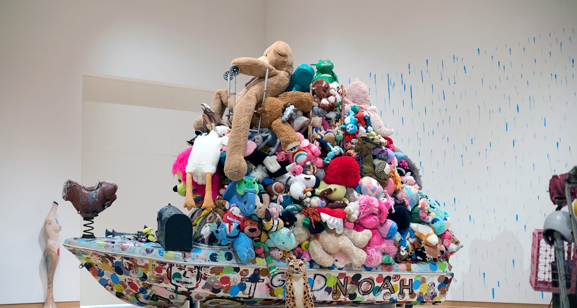 an installation of a bot topped with a tower of stuffed animals by Tyree Guyton against polka dotted walls