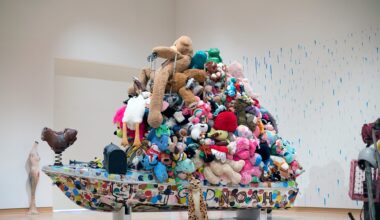 an installation of a bot topped with a tower of stuffed animals by Tyree Guyton against polka dotted walls
