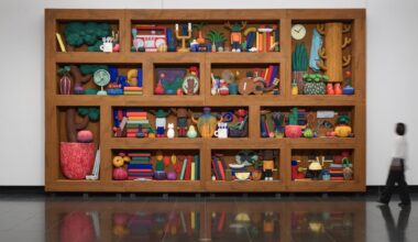 a sculptural installation by Yuichi Hirako of an oversized shelf filled with cartoonish domestic forms like vases, food, candlesticks, and other objects