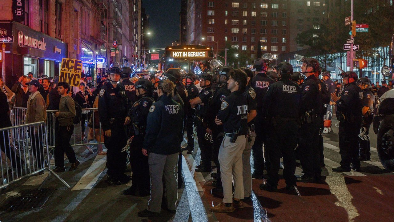 Dozens of police officers stand in the road during a protest against immigration crackdown in the aftermath of a raid on Tuesday, Oct. 21, 2025, in New York. (AP Photo/Olga Fedorova)