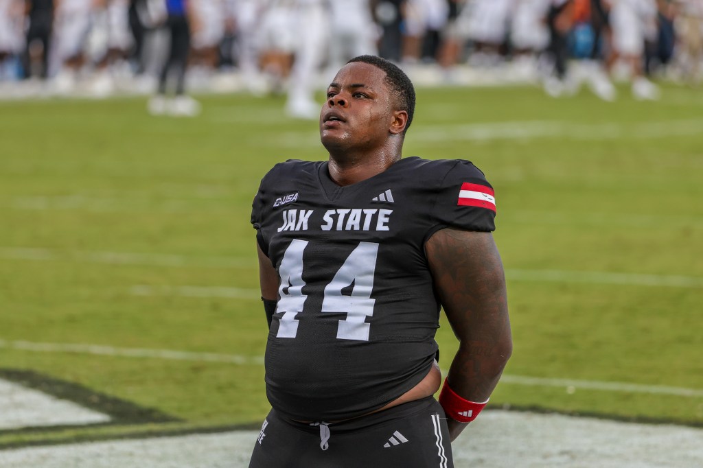 A Jacksonville State Gamecocks football player in a black jersey with the number 44 pauses on the field.
